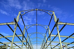 Eisenkonstruktion der Hammelauktionshalle Nahaufnahme der Stahlbögen und Querstreben der Hammelauktionshalle. Der Fokus liegt auf der detailreichen Konstruktion, die sich gegen den strahlend blauen Himmel abhebt.